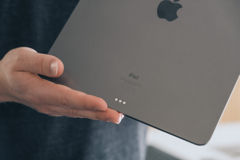 Ein iPad Pro wird in der Hand gehalten. Die Rückseite des iPads wird in die Kamera gezeigt.